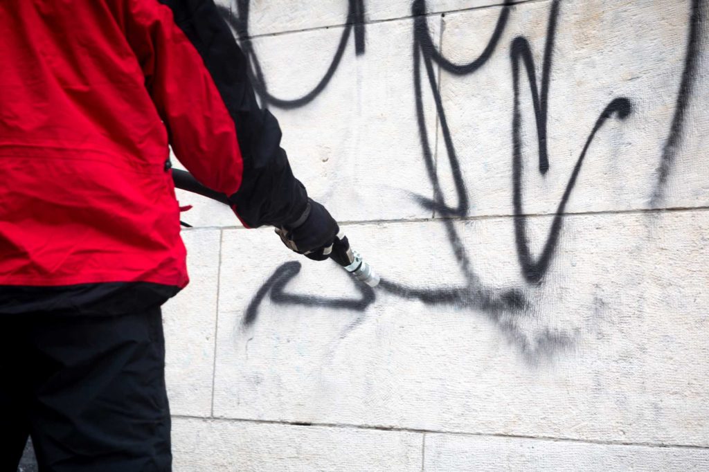 Graffitientfernung Köln Arbeiter an weißer Wand mit Reiniger!